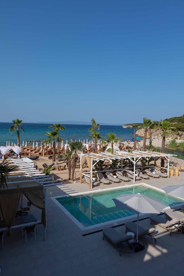 The pool and palm-lined beach bar at Linari, with the sea behind